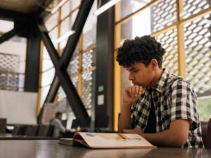 Estudiante escribiendo y concentrado en biblioteca, representando Pomodoro para reducir distracciones y procrastinación.Estudiante escribiendo y concentrado en biblioteca, representando Pomodoro para reducir distracciones y procrastinación.