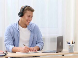 Estudiante con audífonos usando laptop y tomando notas durante un bloque de estudio Pomodoro.