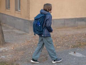Estudiante caminando con mochila al aire libre, asociado a rutina de mañana para regular el sueño.