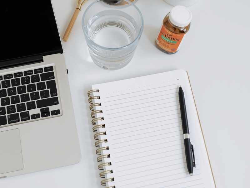 escritorio con laptop, libreta y vitaminas para estudio